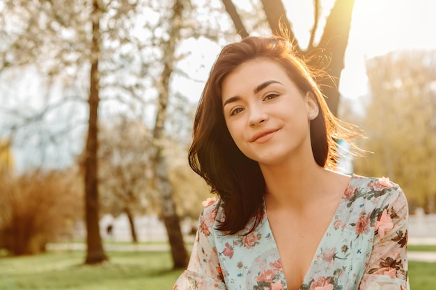 Portrait d'une femme charmante posant près de fleurs de cerisier de pommier en fleurs dans le jardin