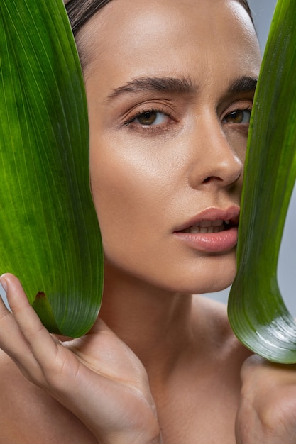 Portrait de femme charmante qui tient des feuilles