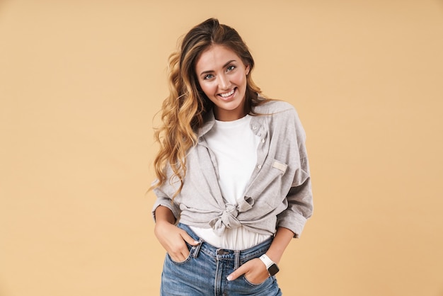 Portrait d'une femme charmante vêtue de vêtements décontractés souriante avec les mains dans les poches isolées