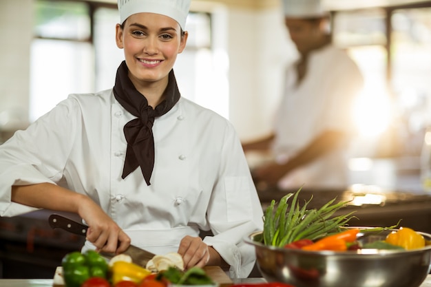 Portrait de femme chef coupe des légumes