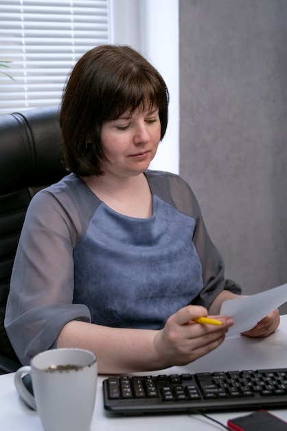 Portrait d'une femme chef d'entreprise dans un bureau privé lors de travaux avec des papiers. Cadre vertical