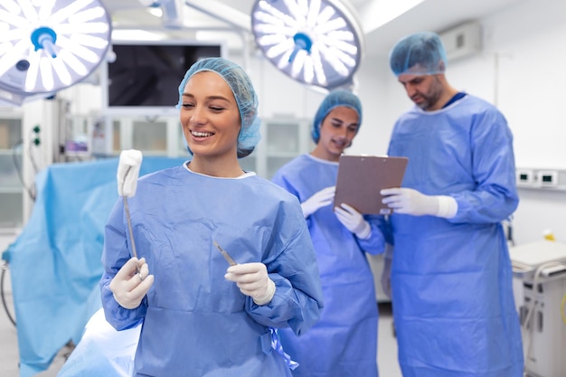 Portrait d'une femme chirurgienne heureuse debout dans la salle d'opération prête à travailler sur un patient Travailleuse médicale en uniforme chirurgical en salle d'opération