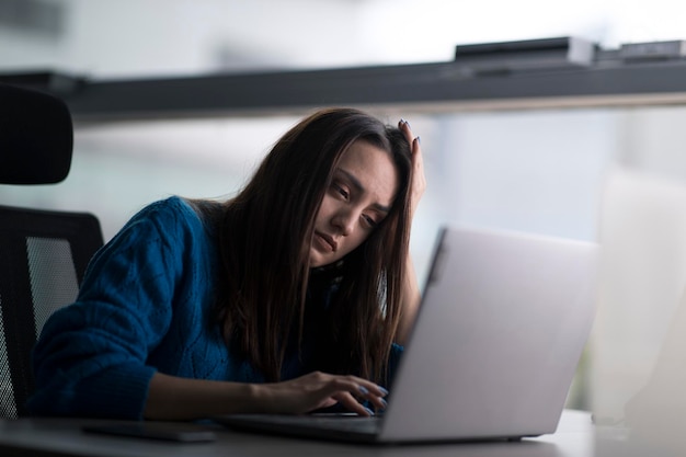 Portrait d'une femme en col blanc fatiguée et sans sommeil, elle cherche un ordinateur portable d'humeur indifférente