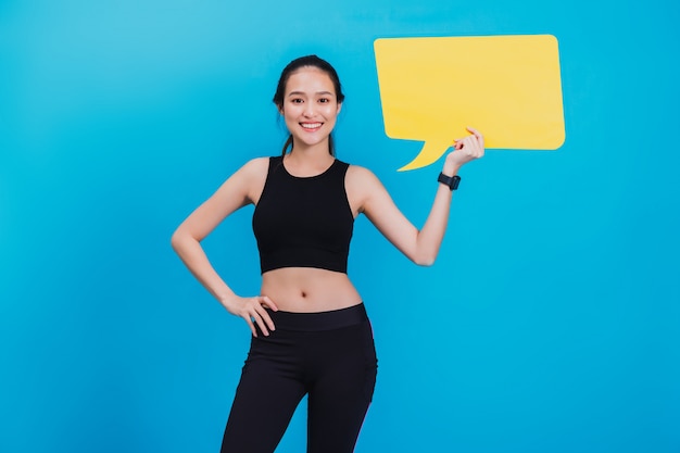 Portrait de femme confiante de remise en forme asiatique belle debout après l'exercice et tenant discours de bulle jaune vide.