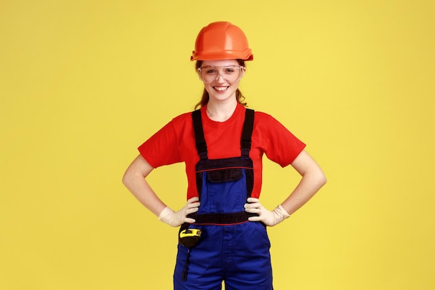 Portrait d'une femme constructeur confiante debout avec les mains sur les hanches regardant la caméra