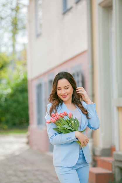 Portrait d'une femme en costume bleu avec un bouquet de tulipes