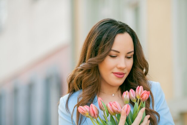 Portrait d'une femme en costume bleu avec un bouquet de tulipes