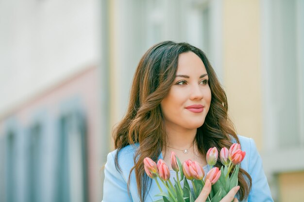 Portrait d'une femme en costume bleu avec un bouquet de tulipes