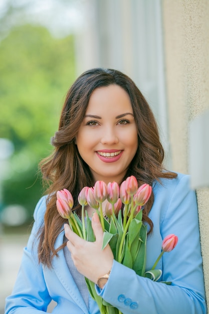 Portrait d'une femme en costume bleu avec un bouquet de tulipes