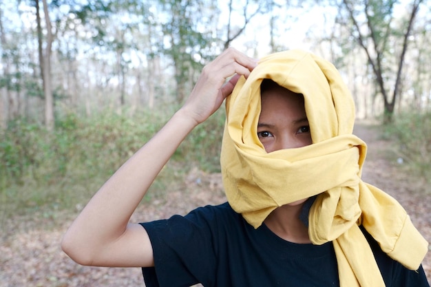 Photo portrait d'une femme couvrant le visage avec un foulard dans la forêt