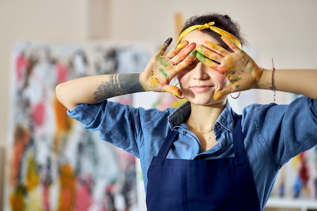 Portrait De Femme Créative Tenant Ses Mains Dans De La Peinture Sur Ses Yeux Tout En Créant Un Résumé