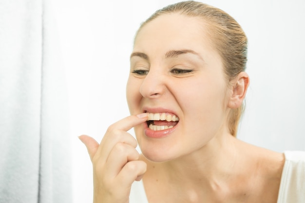 Portrait de femme cueillant des aliments coincés dans les dents avec le doigt