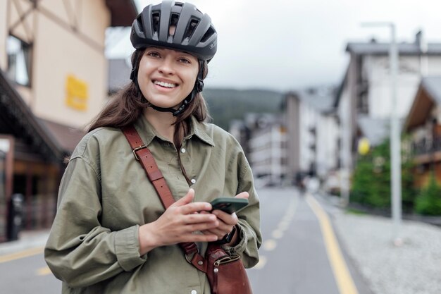 Portrait de femme cycliste avec gadget tout en s'arrêtant sur la piste cyclable de la ville