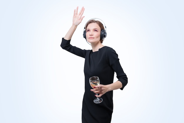 Portrait d'une femme dans des écouteurs professionnels avec un verre de vin à la main. Fond blanc. Concept de DJ. Technique mixte