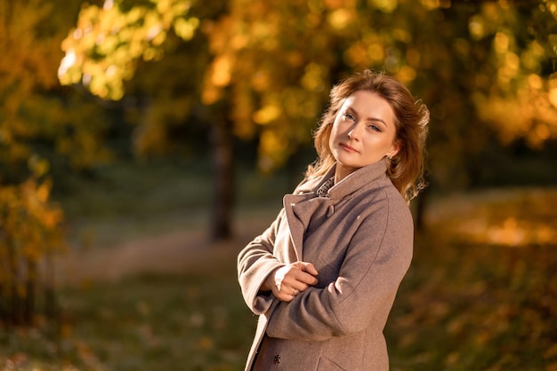 Portrait d'une femme dans un manteau chaud sur le fond des feuilles d'or d'automne