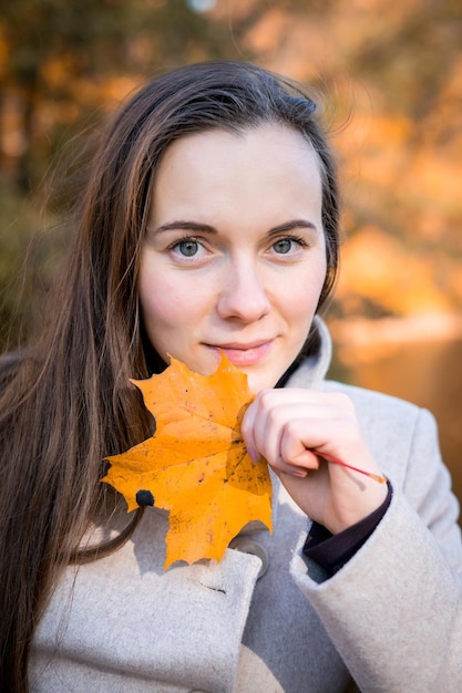 Portrait d'une femme dans un parc d'automne avec des feuilles qui tombent