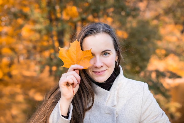 Portrait d'une femme dans un parc d'automne avec des feuilles qui tombent