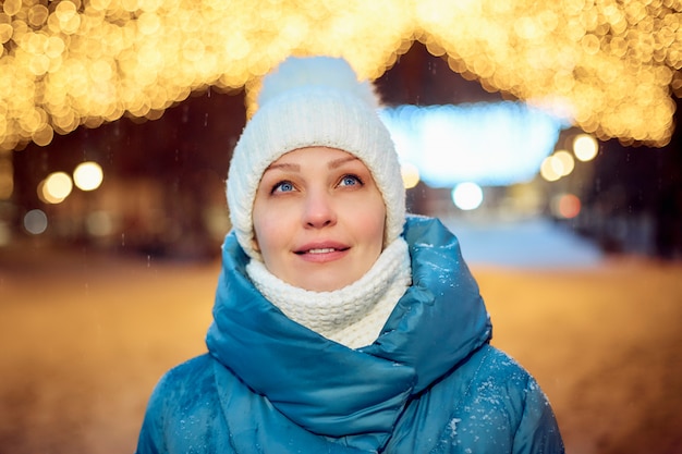 Portrait d'une femme dans un parc d'hiver le soir, décorations de Noël, tourisme et voyages.