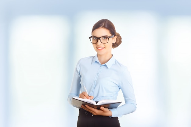 Portrait de femme debout et dressant une liste dans son bureau.