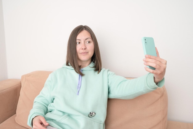 Portrait d'une femme décontractée souriante tenant un smartphone sur fond blanc