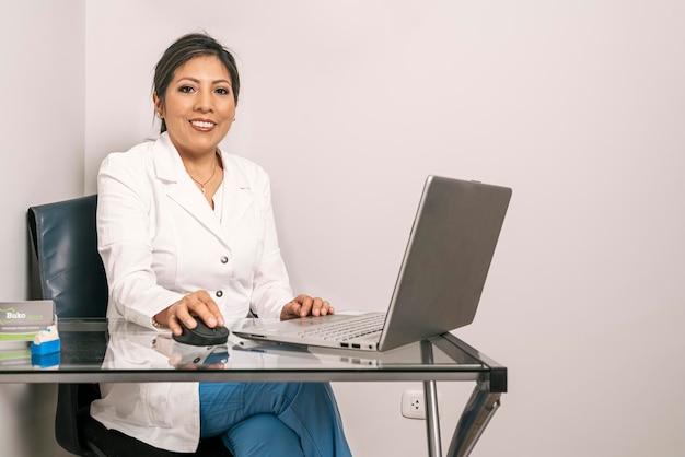 Portrait d'une femme dentiste assise dans un bureau travaillant à l'ordinateur portable