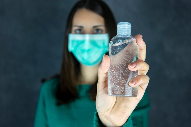 Portrait d'une femme avec un désinfectant pour les mains et un masque de protection