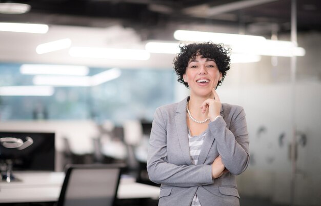 Portrait d'une femme développeur de logiciels réussie avec une coiffure bouclée au bureau de démarrage moderne