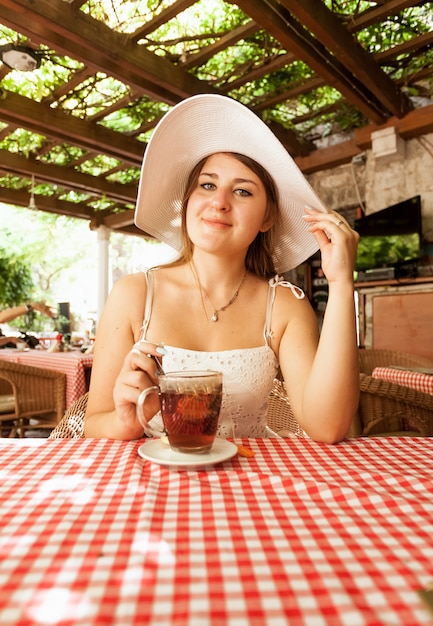 Portrait de femme élégante assise avec une tasse de thé au café