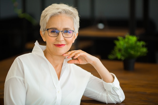 Portrait d'une femme élégante dans une chemise blanche et des lunettes