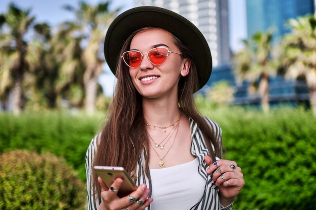 Portrait de femme élégante hipster insouciante portant chapeau de feutre et lunettes rouge vif