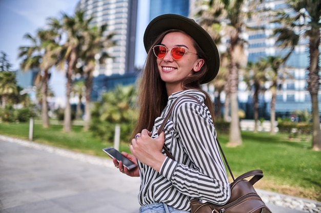 Portrait de femme élégante hipster insouciante portant chapeau de feutre et lunettes rouge vif