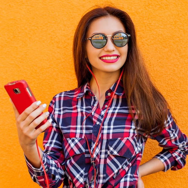 Portrait d'une femme élégante à lunettes de soleil avec du maquillage et des cheveux volants. Urbain