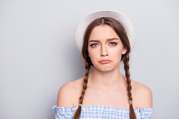 Portrait de femme élégante avec des nattes posant contre le mur gris