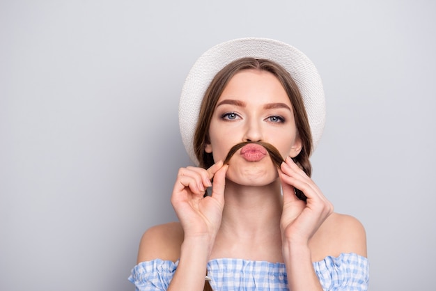 Portrait de femme élégante avec des nattes posant contre le mur gris