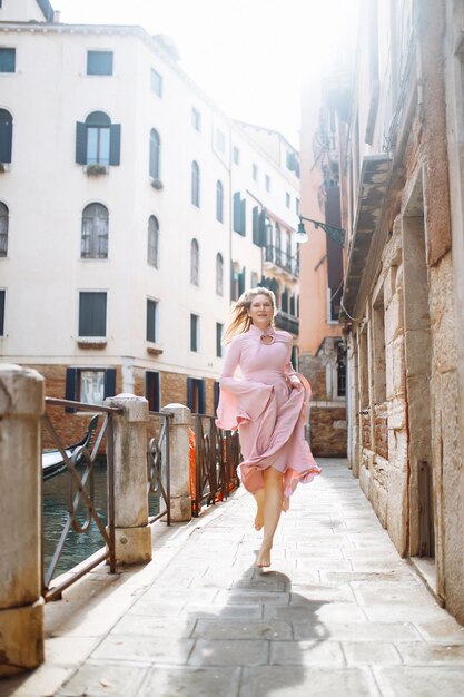 Portrait d'une femme élégante en robe rose se promène dans les rues ensoleillées de Venise Concept de voyage