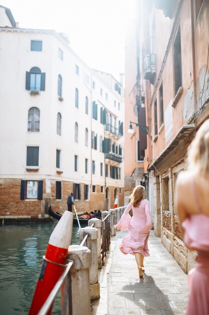 Portrait d'une femme élégante en robe rose se promène dans les rues ensoleillées de Venise Travel concept