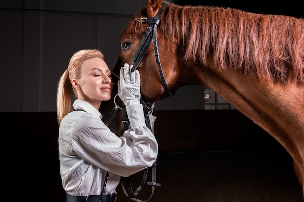 Portrait d'une femme élégante serrant un cheval pur-sang. Concept d'amour et de soins.