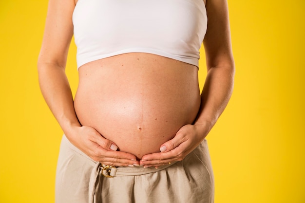 Portrait de femme enceinte de 9 mois sur mur jaune