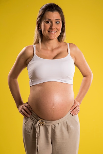 Portrait de femme enceinte de 9 mois sur mur jaune