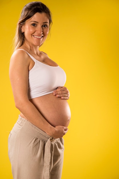 Portrait de femme enceinte de 9 mois sur mur jaune