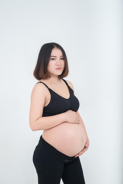Portrait de femme enceinte asiatique sur fond blancles gens de thaïlande utilisent le ventre tactile de la main