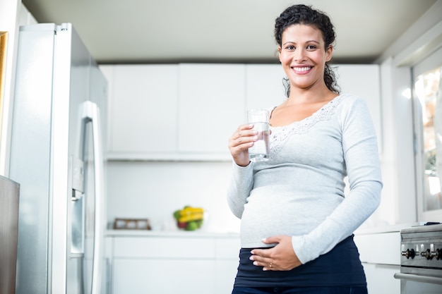 Portrait de femme enceinte heureuse tenant un verre d&#39;eau