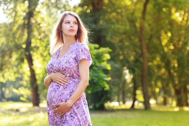 Portrait d'une femme enceinte marchant vers la caméra regardant à côté dans un parc