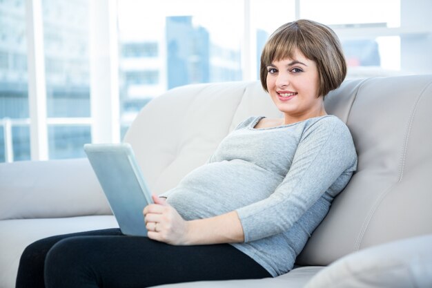 Portrait de femme enceinte souriante à l&#39;aide de tablette numérique