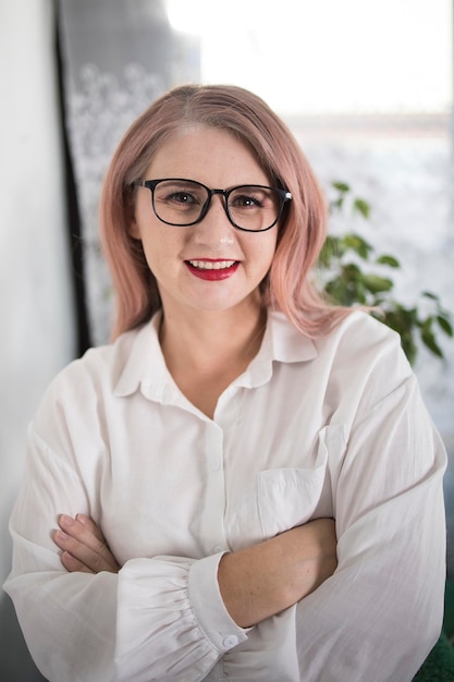 Portrait d'une femme entrepreneure adulte aux cheveux grisâtres dans un poste de direction vêtue d'une blouse blanche et occupée à travailler au bureau