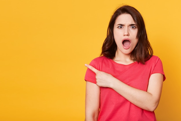 Portrait de femme étonnée se tient isolé sur jaune