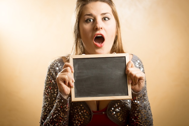 Photo portrait d'une femme étonnée tenant un tableau blanc dans les mains