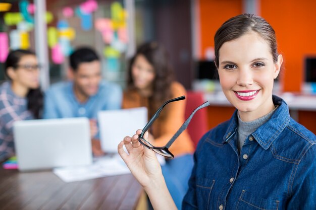 Portrait de femme exécutive souriante debout avec des lunettes