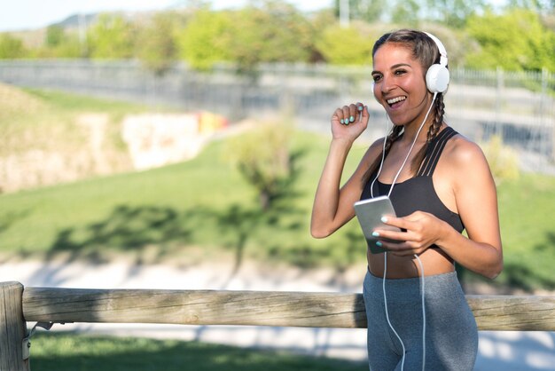 Portrait d'une femme faisant du sport au repos en plein air souriant et écoutant de la musique