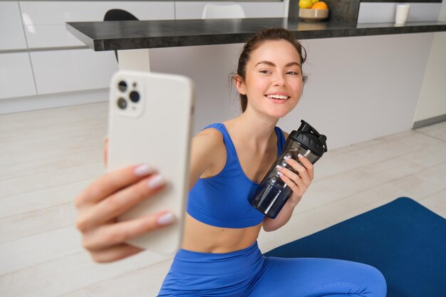 Portrait d'une femme faisant du sport prend un selfie sur un smartphone, un instructeur de fitness enregistre ses exercices